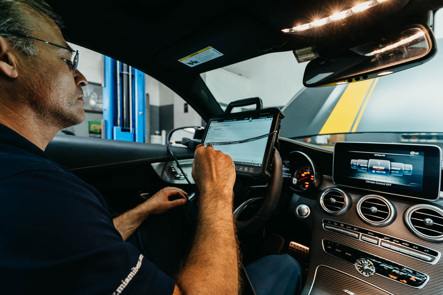 Miami Benz technician calibrates a luxury car's system using diagnostic equipment in South Miami workshop.