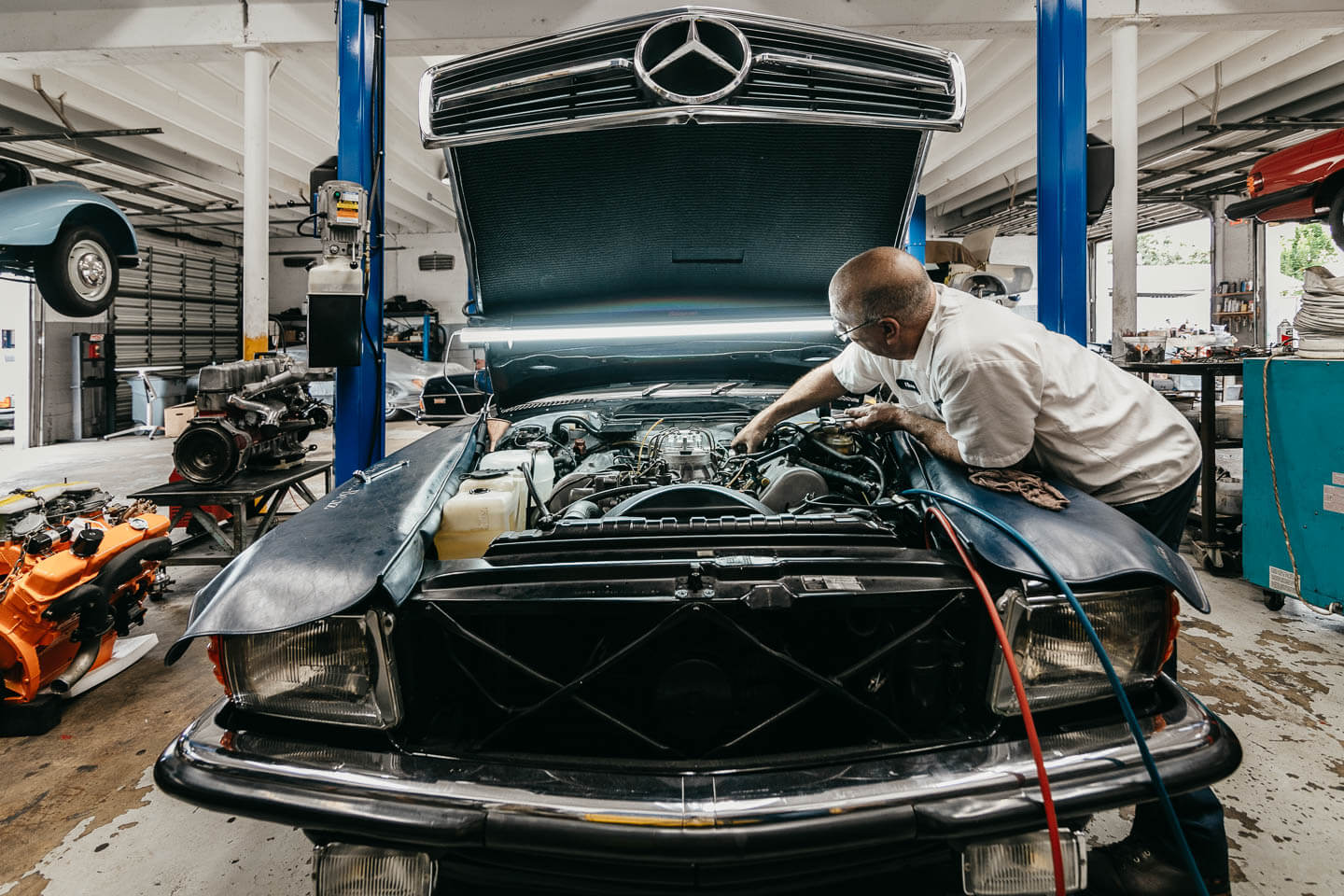 Expert technician meticulously servicing the engine of a classic Mercedes-Benz at Miami Benz workshop.