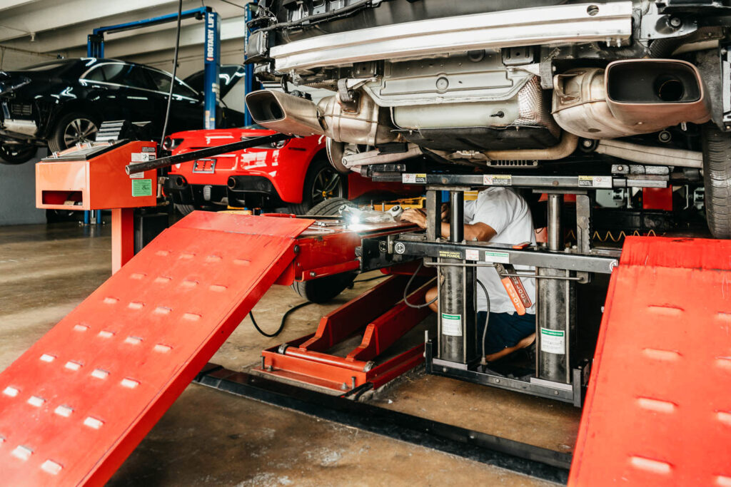 Miami Benz technician inspecting the underside of a Mercedes-Benz on a lift in South Miami