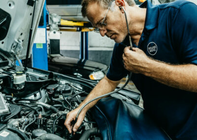 A skilled Miami Benz technician in South Miami meticulously adjusts a car's engine, showcasing local expertise in luxury auto care.