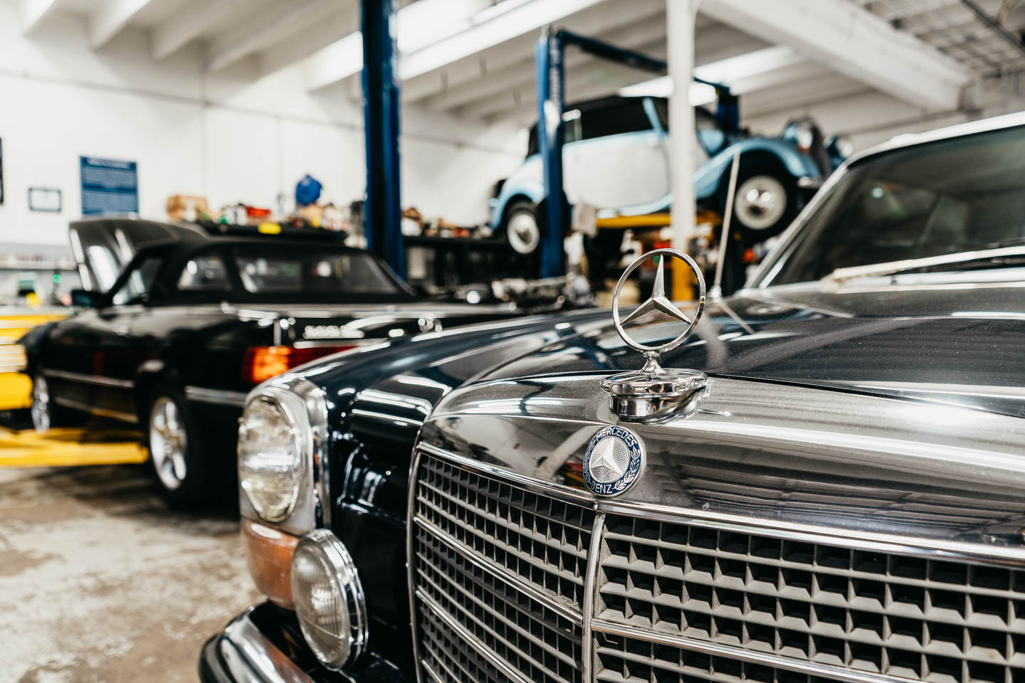Close-up of the iconic Mercedes-Benz emblem on a restored classic model in the Miami Benz workshop.