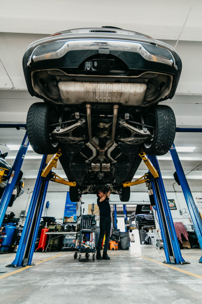 Underside of a modern Mercedes-Benz raised on a hydraulic lift during a specialist inspection