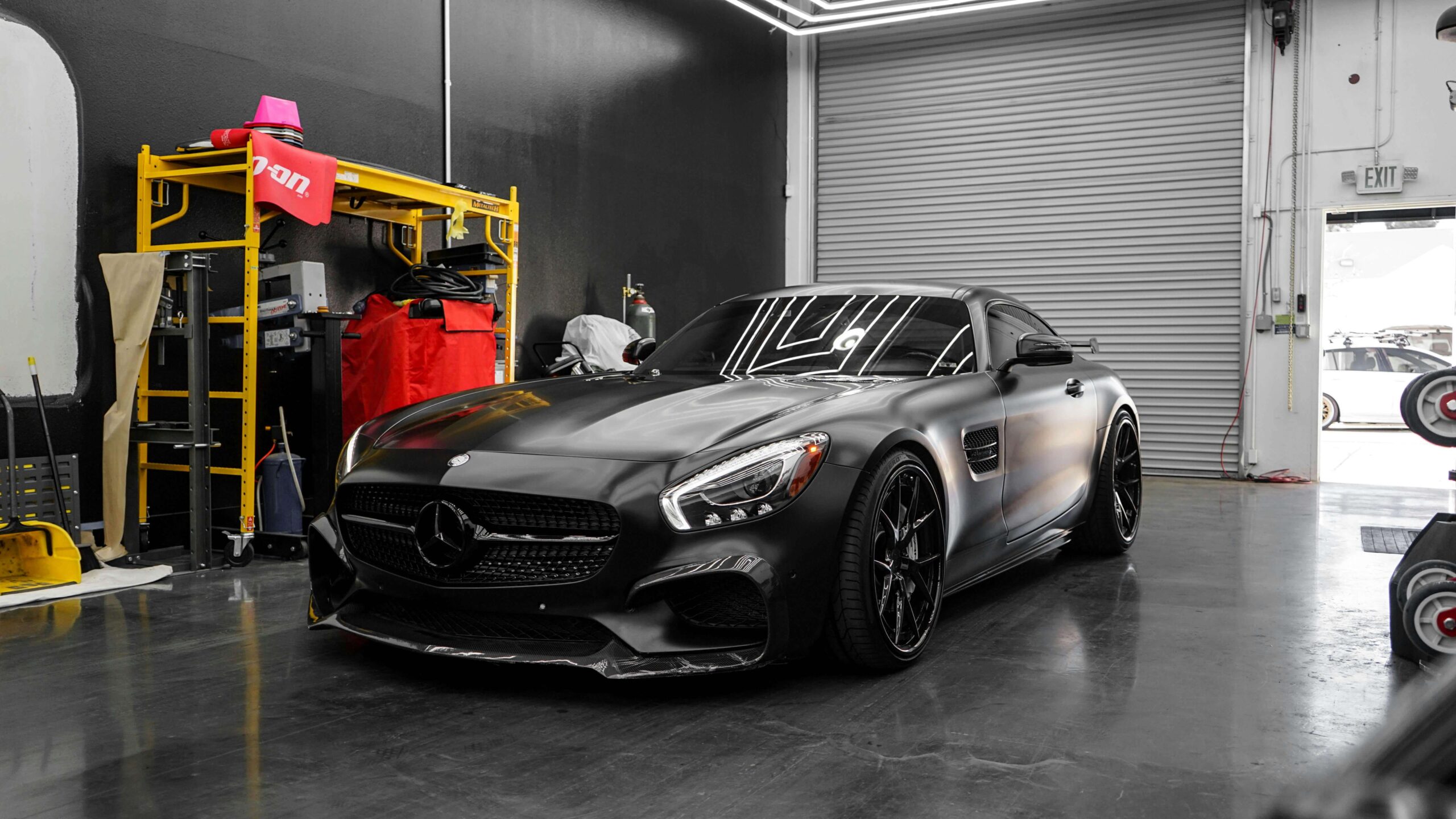 Matte black Mercedes-Benz sports car parked in a garage workshop.