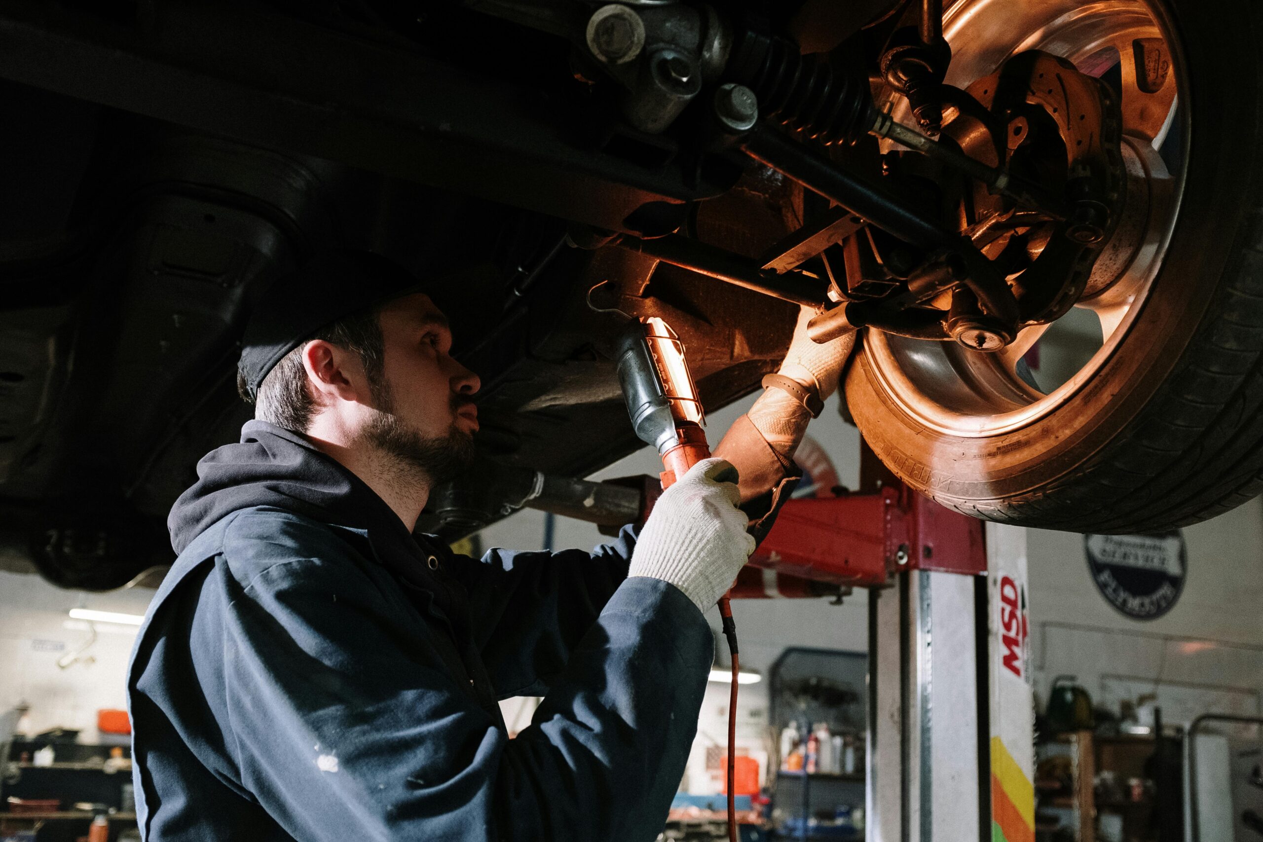 A mechanic working on the undercarriage of a Sprinter van as part of routine fleet maintenance.