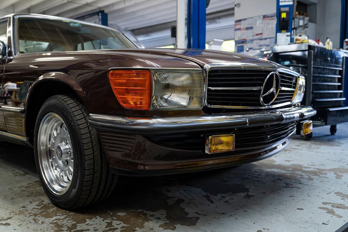 Front three-quarter view of a brown classic Mercedes-Benz SL inside the Miami Benz workshop.