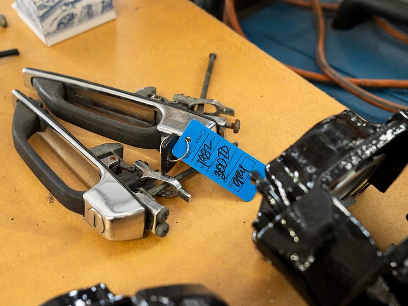 Tagged door handles and brake calipers laid out on a workbench at Miami Benz.