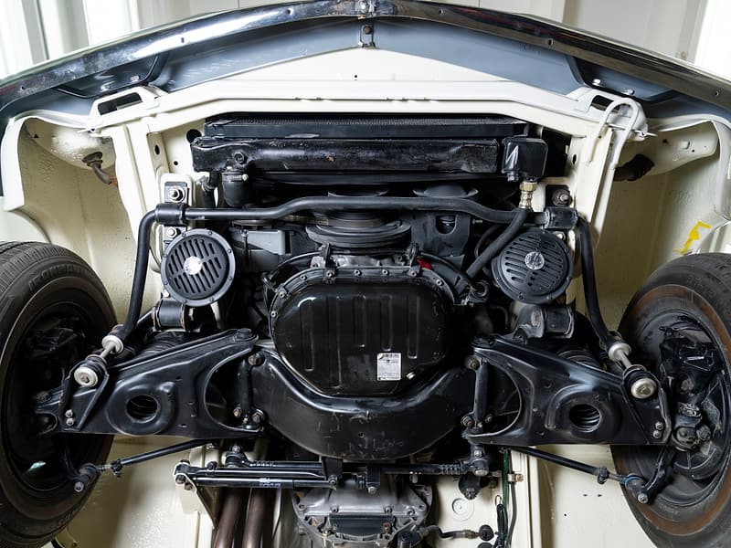 Underside of a cream classic Mercedes-Benz on a lift, showing its chassis and suspension.