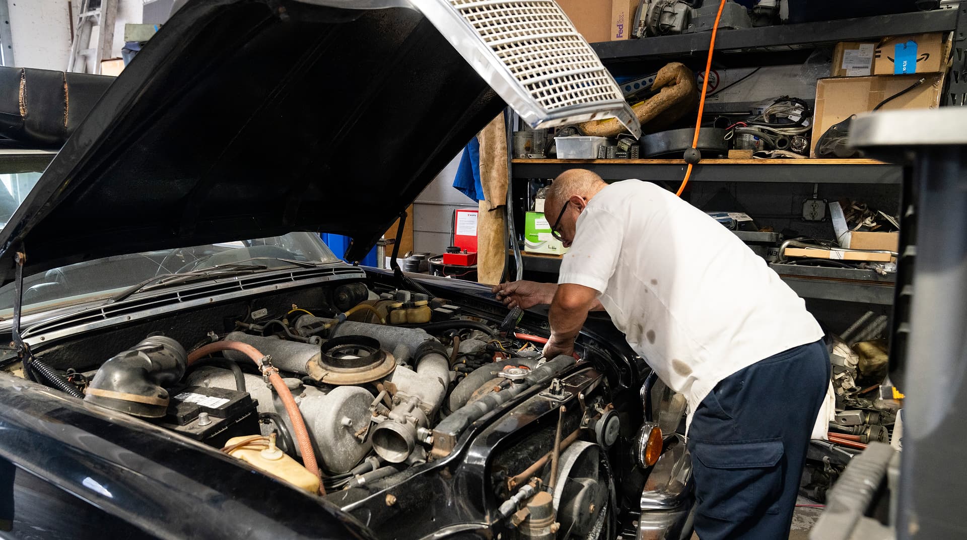 Working in the Engine Bay Miami Benz technician leaning into the engine bay of a car in the South Miami workshop.