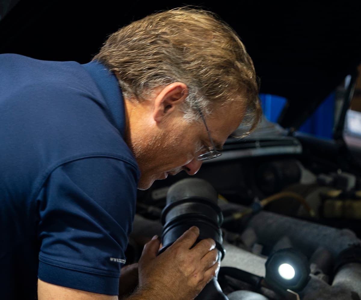 Miami Benz technician checking an engine bay with an inspection light.