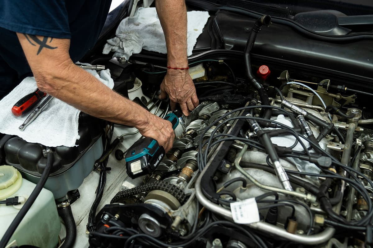 Hands of a Miami Benz technician working on top of an engine in the South Miami workshop.