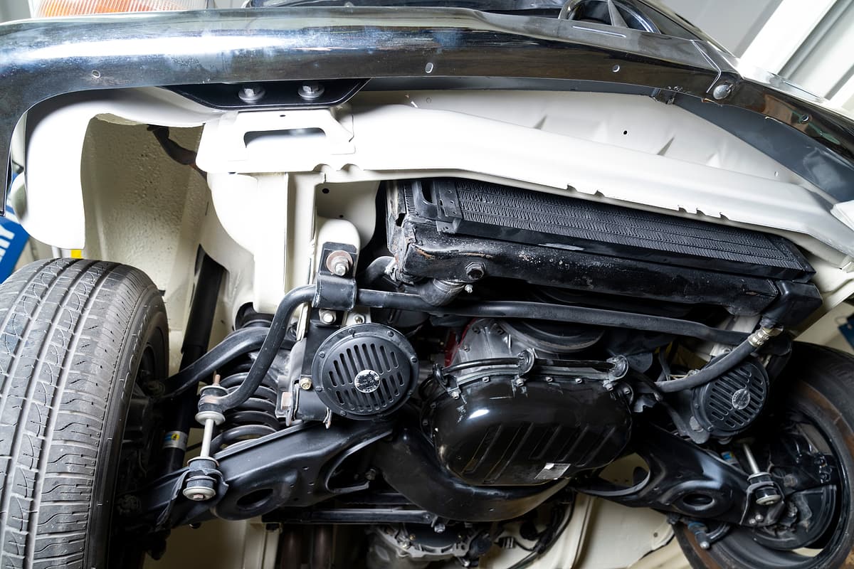 Front suspension and subframe of a car on a lift, seen from below.
