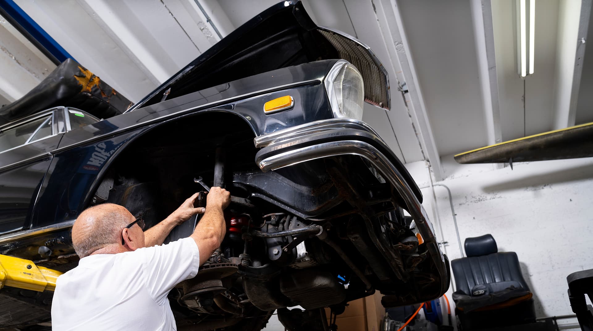 Working on the Front Suspension Miami Benz technician working on the front suspension of a car on a lift in the South Miami workshop.
